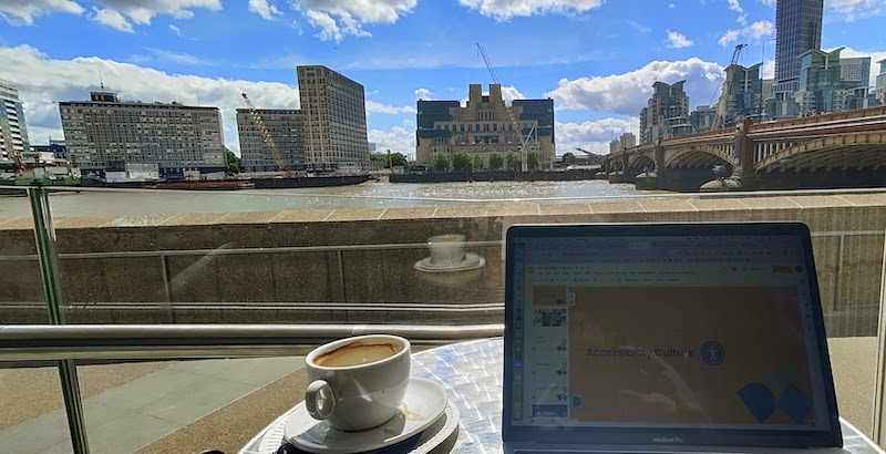 Coffee and laptop with presentation on a table and view of MI6 in London from north riverside
