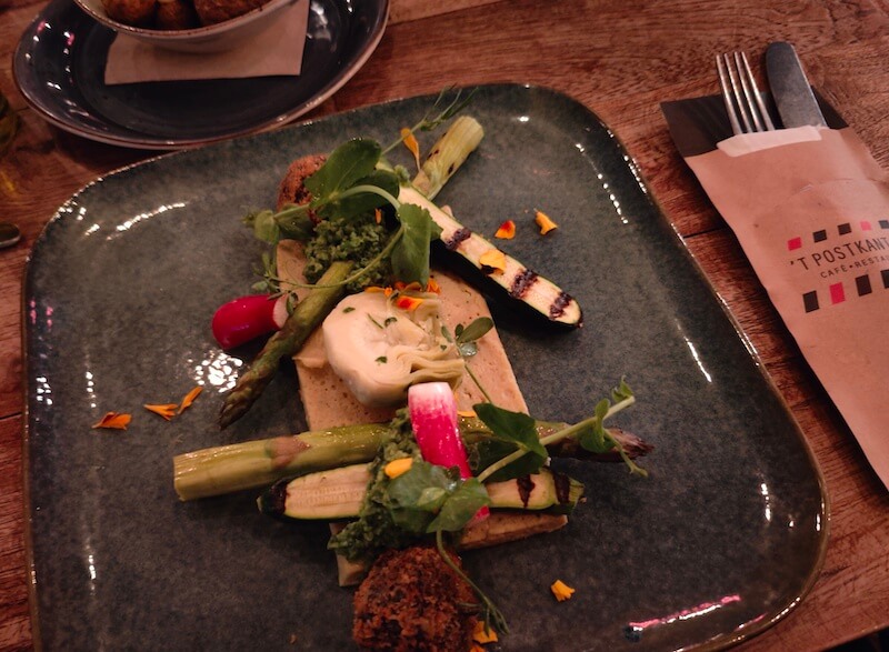 Square dish of marinated artichoke, crispy black bean risotto balls and grilled asparagus