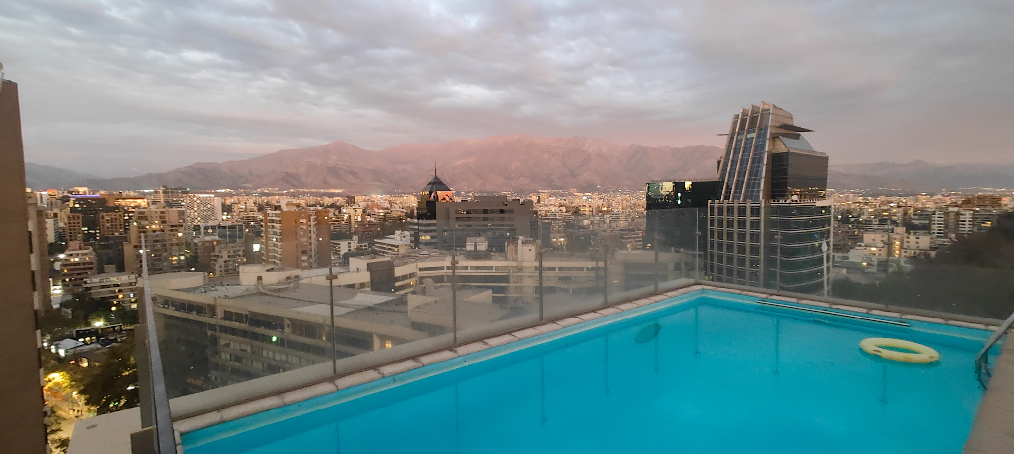 Rooftop pool with backdrop of Santiago skyline at dusk