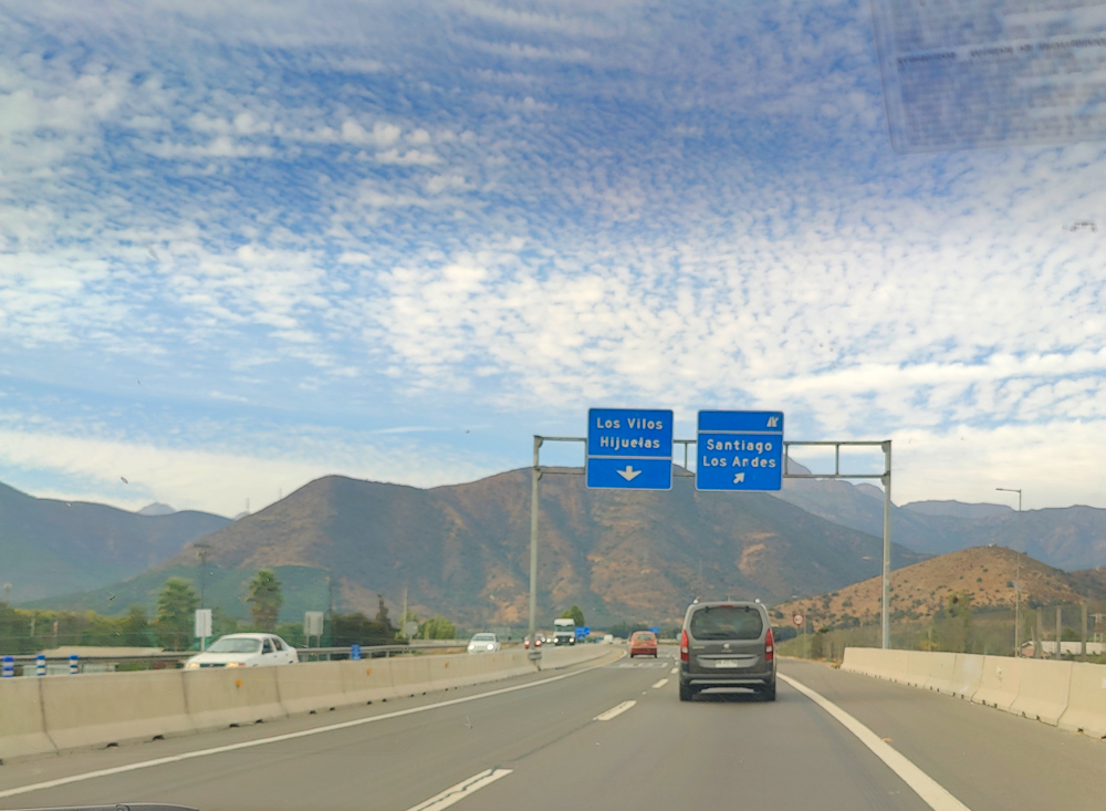 Highway with Andes in backdrop and blue signage to Santiago