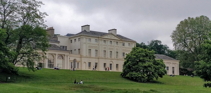 Landscape view of Kenwood House with foreground of grass and trees in full bloom