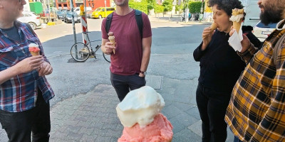 Holding a cone of ice cream with vanilla and rhubarb. Backdrop of other btconf attendees