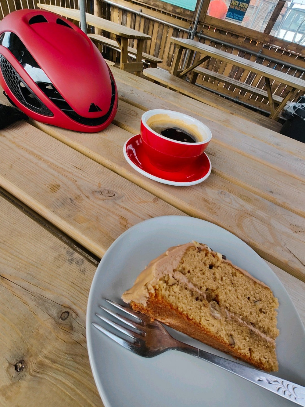 Coffee and walnut cake with coffee. Red Canyon helmet on a table