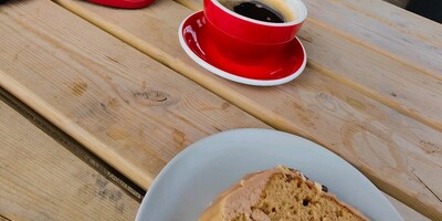 Coffee and walnut cake with coffee. Red Canyon helmet on a table