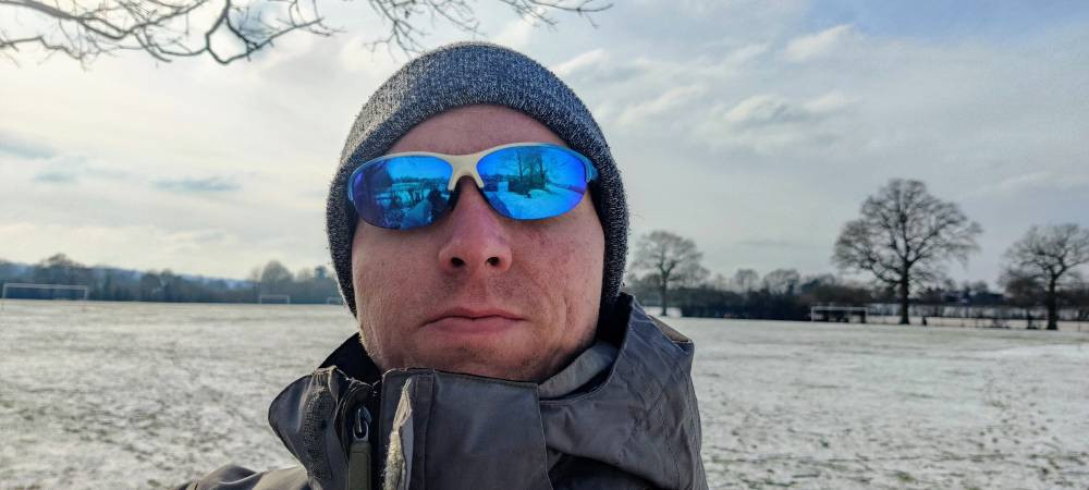 Calum wearing blue sun glasses at a snow-covered field in Tonbridge