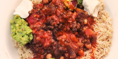 Vegan chili dish surrounded with brown rice