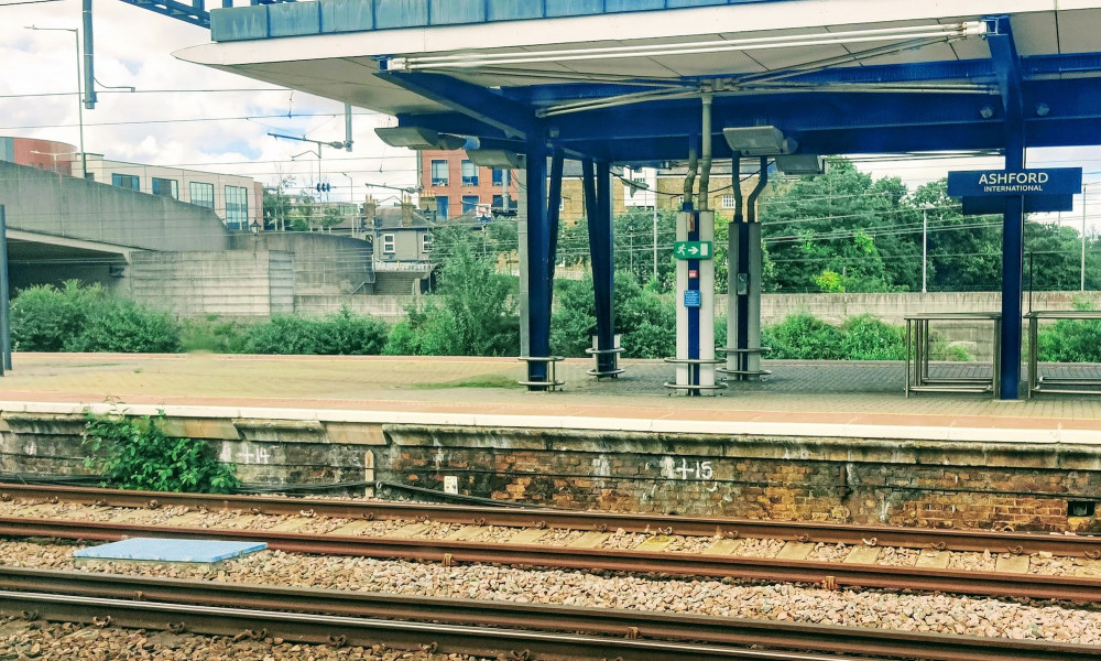 Ashford International station with green foliage growing alongside the platform edge