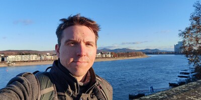 Calum profile shot with backdrop of Rhine river and hills in Bonn with clear blue sky