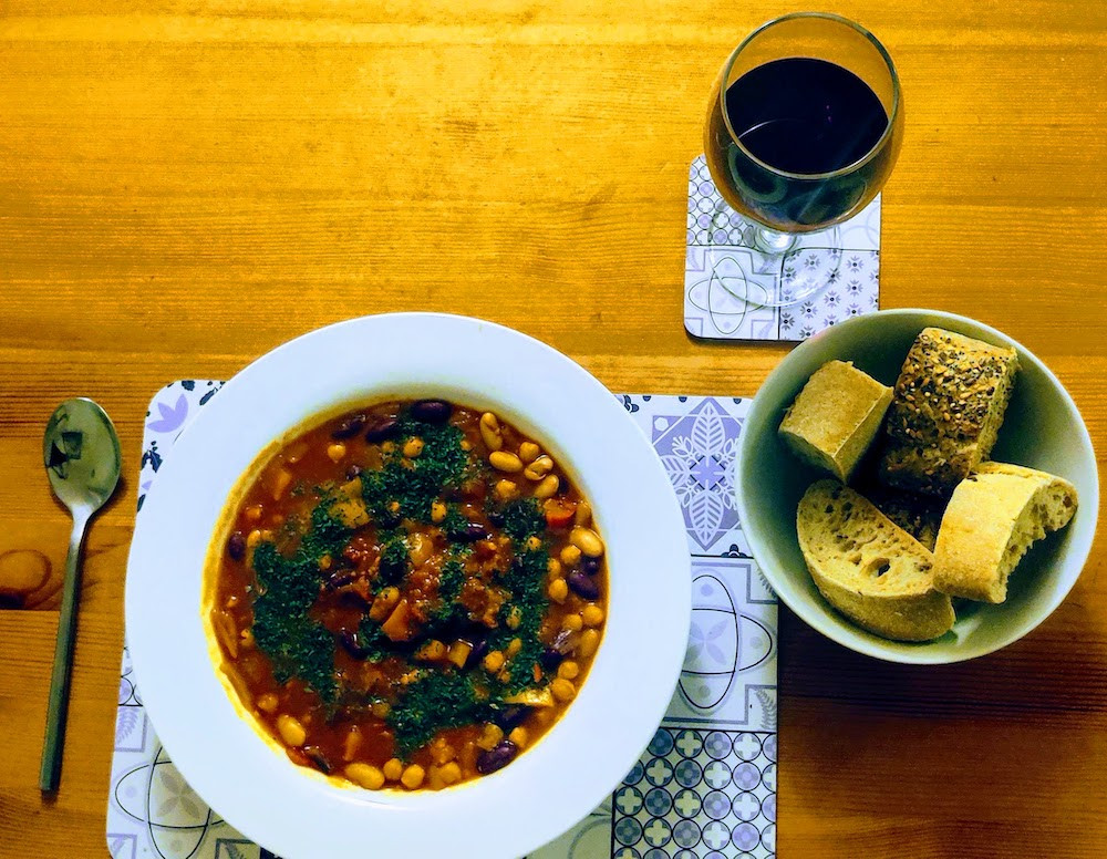 Bean stew in a white plate with bread and red