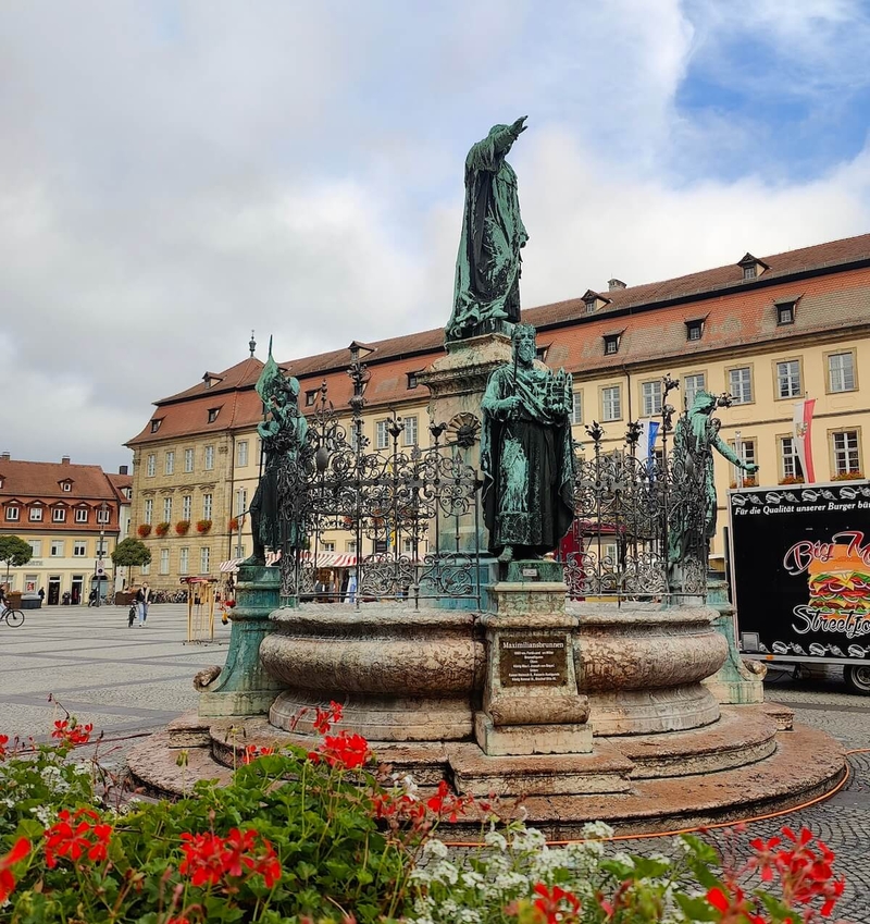 Market square view with statue in the centre and red flowers in foreground