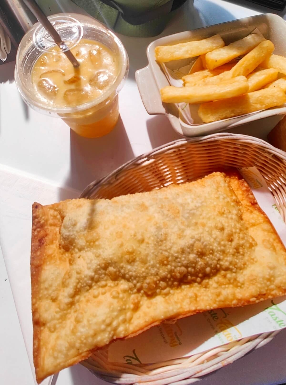 Pastel de carne, a plate of Yuca fried with a plastic galss of passion fruit juice