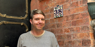 The house number 38 on ceramic tiles with a pretty backdrop of a black door, Calum stand beside