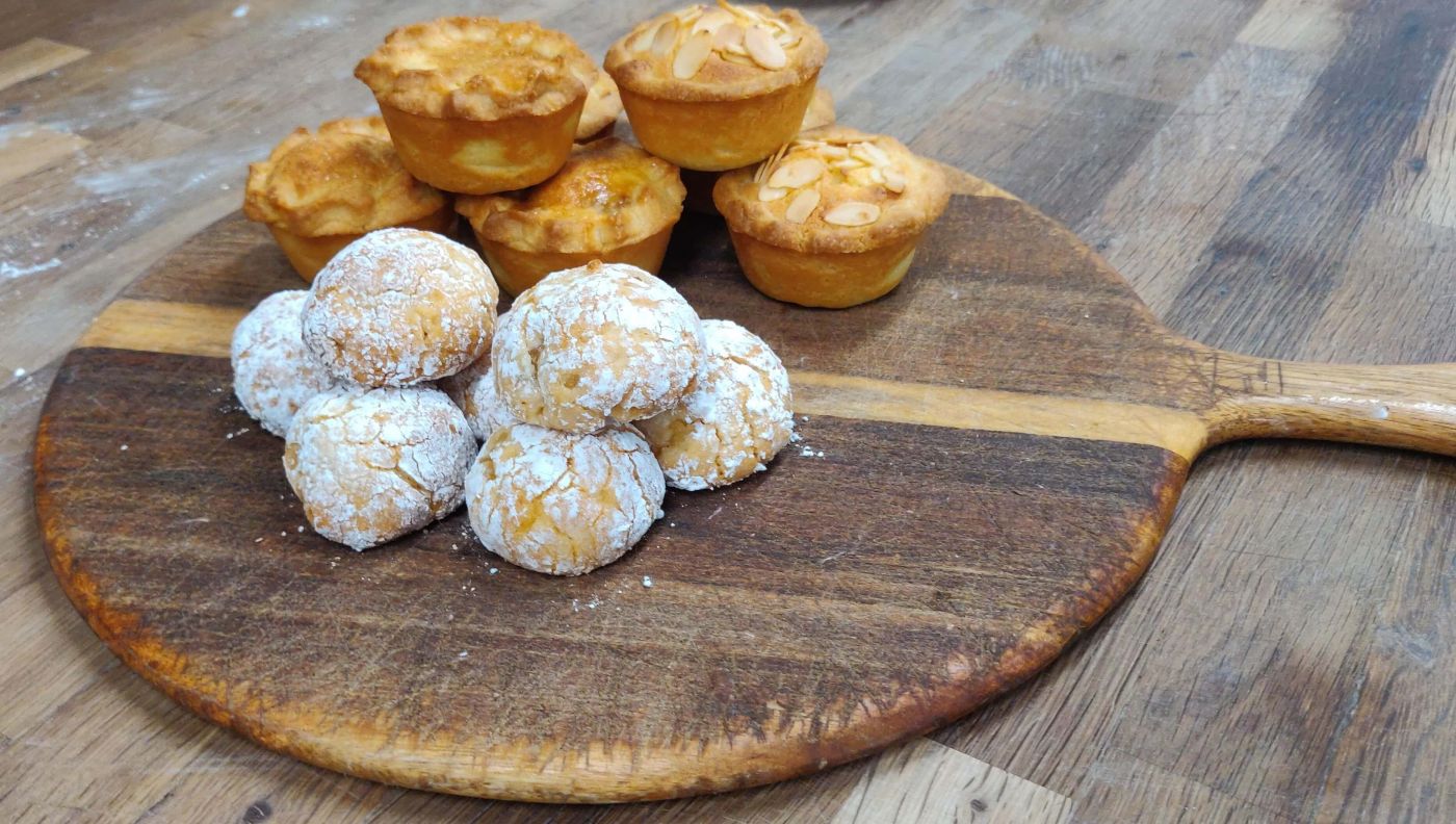 Freshly baked mince pies and amaretti biscuits on a round wooden board